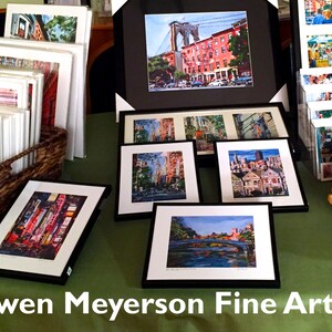 Puede incluir: Una mesa con una exposici&oacute;n de obras de arte enmarcadas que representan paisajes urbanos y puentes. Las obras est&aacute;n en marcos negros con paspart&uacute;s blancos. La mesa est&aacute; cubierta con un mantel verde. El texto "Gwen Meyerson Fine Art" es visible en la parte inferior de la imagen.