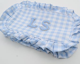 Puede incluir: Una almohada rectangular con un estampado de cuadros vichy azul claro y blanco, con un borde con volantes. La almohada presenta las letras "LS" en una fuente azul claro con cuentas.