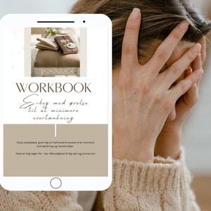 Könnte beinhalten: Ein Smartphone zeigt ein Arbeitsbuch mit dem Titel "WORKBOOK E-bog med øvelse til at minimere overtænkning." Das Bild auf dem Telefon zeigt ein Buch und ein Notizbuch auf einer gepolsterten Oberfläche. Eine Person hält sich den Kopf.