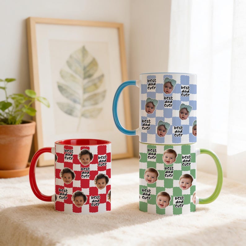 May include: Three ceramic mugs with the text "best dad ever" and baby faces. One mug has a red and white checkered pattern with a red handle. The other two mugs have blue and green checkered patterns with blue and green handles.