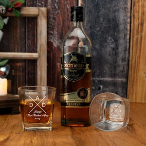 Op de afbeelding: Een fles Knight Whisky en twee gegraveerde whiskyglazen op een houten oppervlak. De glazen zijn gegraveerd met "Happy First Father's Day 2025". De fles heeft een zwart en goudkleurig etiket.