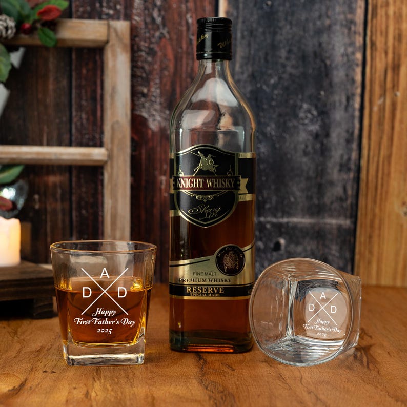 Op de afbeelding: Een fles Knight Whisky en twee gegraveerde whiskyglazen op een houten oppervlak. De glazen zijn gegraveerd met "Happy First Father's Day 2025". De fles heeft een zwart en goudkleurig etiket.