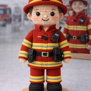 May include: Crocheted firefighter doll in red, yellow, and black uniform, complete with a helmet and radio. The doll is standing on a wooden base with the name "Firefighter Jack" engraved. A second doll is visible in the background.