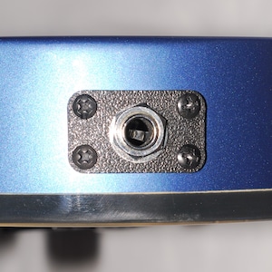 May include: Close-up of a blue electric guitar with a black output jack.