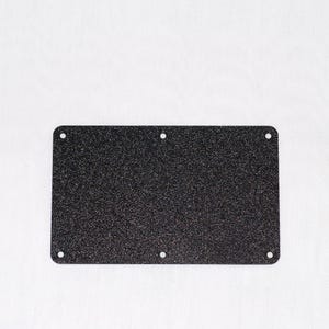 May include: A rectangular, dark speckled metal plate with rounded corners and six evenly spaced holes. The plate has a textured surface and is set against a white background.