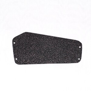 May include: A black, textured guitar backplate with a speckled appearance. The plate has an asymmetrical shape with four screw holes. The background is plain white.