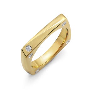 Può includere: Un anello color oro dal design rettangolare. L'anello presenta piccole gemme rotonde e trasparenti incastonate nella fascia d'oro. L'anello è mostrato su sfondo bianco.