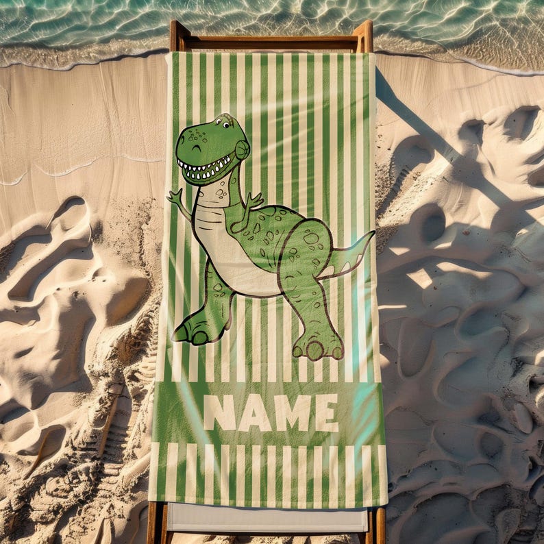 May include: Green and white striped beach towel with a cartoon green dinosaur and the word "NAME" printed on it.