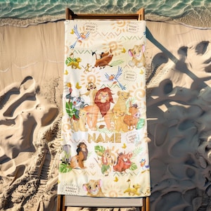 May include: A rectangular beach towel featuring characters from The Lion King. The towel has a cream background with illustrations of Simba, Timon, Pumbaa, and other characters. The words "Hakuna Matata" are printed on the towel, along with a space for a name.