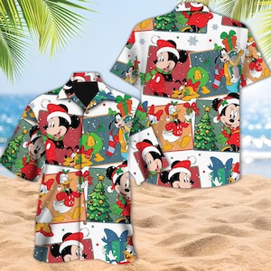 May include: A short-sleeved button-down shirt featuring a festive Christmas-themed pattern. The design includes cartoon characters like Mickey Mouse, Donald Duck, and Goofy, wearing Santa hats and surrounded by Christmas trees and gifts. The shirt has a white background with colorful squares.