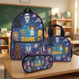May include: A backpack, lunch bag, and pencil case set featuring a dark blue space background with cartoon Star Wars characters including Darth Vader, Yoda, and R2-D2. Each item displays the name JAME in yellow text on the front pocket area.
