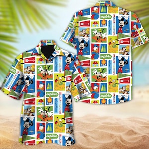 May include: A white button-up shirt with a colorful pattern featuring Mickey Mouse, Goofy, Donald Duck, and Pluto. The pattern includes the words "explore" and "adventure".