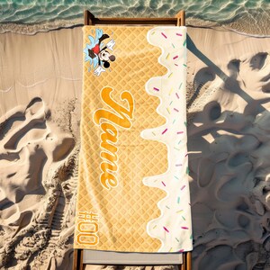 May include: A yellow and white beach towel with a waffle pattern. The towel has a cartoon image of Mickey Mouse and the text "#000" and "Name" printed on it.
