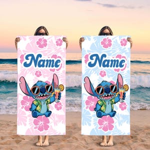 May include: Two beach towels, one pink and one blue, each featuring a cartoon character wearing sunglasses and holding a tropical drink. The towels have a floral pattern and the word "Name" in script.