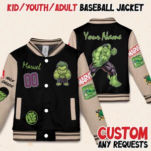 May include: Black baseball jacket with beige sleeves featuring Hulk graphics and the text "Marvel". The jacket has a striped collar and cuffs, and the text "Hulk Smash!" is on the sleeve. The back of the jacket has a large Hulk graphic and the text "Your Name".
