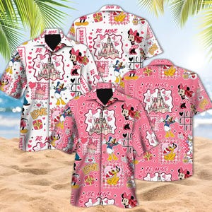 May include: Four short-sleeved button-down shirts with a Valentine's Day theme. The shirts feature Minnie Mouse, Donald Duck, castles, hearts, and the words "BE MINE" and "LOVE" on a white and pink background. The shirts are displayed on a sandy beach.