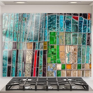 Puede incluir: Un salpicadero de vidrio de colores con un diseño de mosaico. El salpicadero presenta piezas rectangulares de vidrio en tonos turquesa, verde, rojo y dorado. Está instalado sobre una cocina de gas de acero inoxidable.
