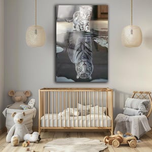 Könnte beinhalten: Ein gerahmter Wandkunstdruck zeigt eine Katze und ihr Spiegelbild als Tiger. Die Katze ist grau und weiß und steht über ihrem Spiegelbild in einer dunklen, wasserartigen Oberfläche. Das Tiger-Spiegelbild ist weiß mit schwarzen Streifen.