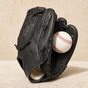 Peut inclure: Un gant de baseball noir avec un design en toile tressée, des lacets en cuir noir et une balle de baseball blanche aux coutures rouges à l'intérieur. Le gant est personnalisé avec le nom Hayes et le numéro #07 gravés sur la surface extérieure.