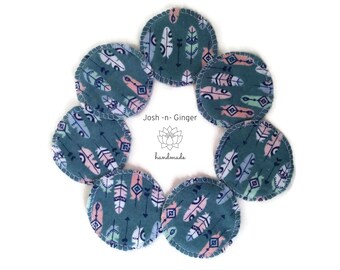 May include: Eight teal blue reusable makeup remover pads with a pink and green feather pattern. The pads are arranged in a circle with the text "Josh-n-Ginger handmade" in the centre.
