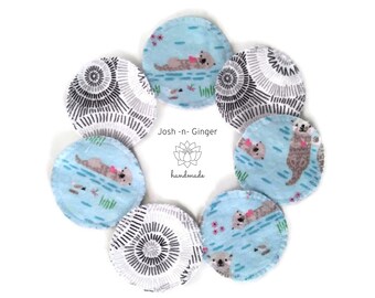 May include: A set of eight handmade reusable cotton rounds featuring a blue and white pattern with otters. The rounds are arranged in a circle with the text "Josh - n - Ginger handmade" in the centre.