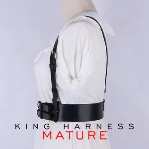 May include: Black leather body harness with adjustable straps and a wide belt. The harness features metal hardware and is designed to be worn over clothing. The text "KING HARNESS MATURE" is printed at the bottom of the image.