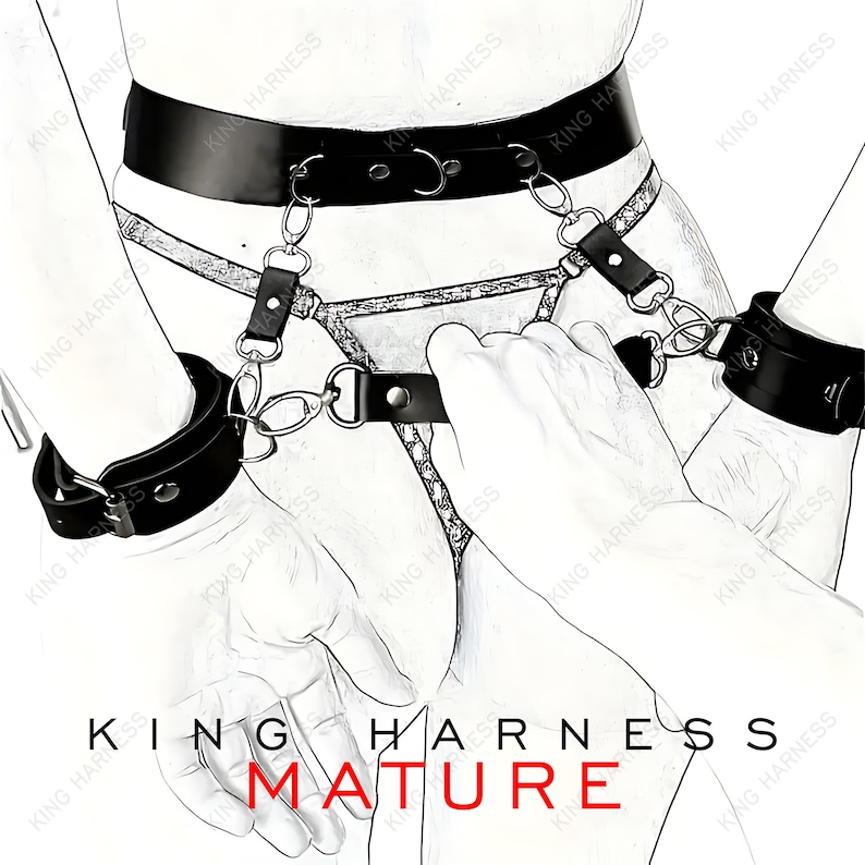 Puede incluir: Arn&eacute;s de cuero negro con detalles de cadena y esposas a juego. El arn&eacute;s tiene un cintur&oacute;n con hebilla y dos correas que se conectan a las esposas. El texto "KING HARNESS MATURE" est&aacute; impreso debajo de la imagen.