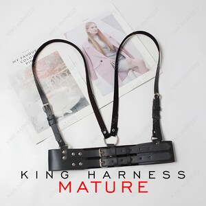 May include: Black leather harness with adjustable straps and silver-tone buckles. The harness features a double-belt design and a metal ring. The text "KING HARNESS MATURE" is visible.