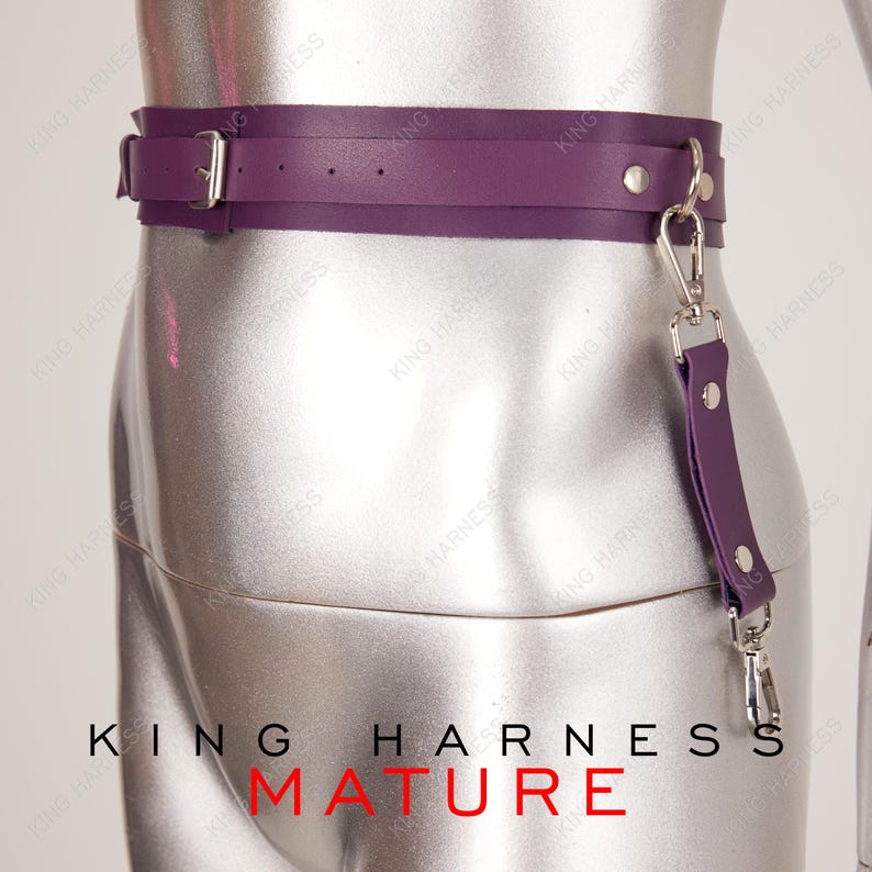 Puede incluir: Cintur&oacute;n de cuero morado con hebilla plateada y una correa de cuero morado a juego con un clip plateado. El texto "KING HARNESS MATURE" est&aacute; impreso debajo del cintur&oacute;n.