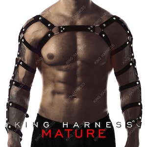 May include: Black leather harness with silver-tone rivets and metal rings. The harness features straps across the shoulders, chest, and arms. The text "KING HARNESS" and "MATURE" are visible at the bottom of the image.