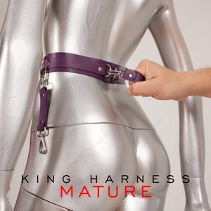 Puede incluir: Arn&eacute;s de cuero morado con herrajes plateados y un anillo en D. El arn&eacute;s se lleva en un maniqu&iacute; plateado. El texto "KING HARNESS MATURE" est&aacute; impreso en la parte inferior de la imagen.