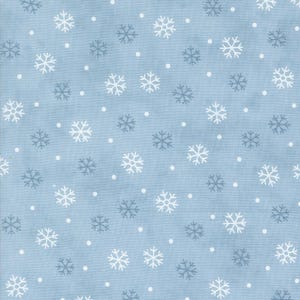 Op de afbeelding: Een lichtblauwe stof met een herhalend patroon van witte en donkergrijze sneeuwvlokken, afgewisseld met kleine witte stippen. Het textiel heeft een geweven textuur en toont een consistent, gelijkmatig verdeeld winterthema over het oppervlak.