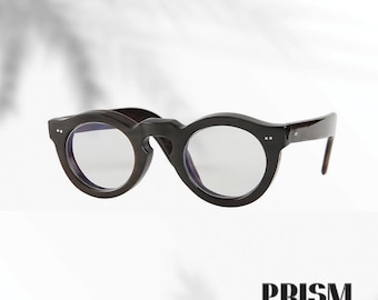 Könnte beinhalten: Dunkelbraune Brille mit runden Gläsern und klaren Gläsern. Die Brille hat einen dicken Rahmen und einen Schlüssellochsteg. Der Markenname "PRISM" wird unten im Bild in fetter, serifenloser Schrift angezeigt.