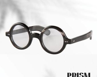 Könnte beinhalten: Runde schwarze Brille mit klaren Gläsern. Die Fassungen haben eine dunkle Holzmaserung. Das Bild enthält das Wort "PRISM" in fetter, serifenloser Schrift unten.