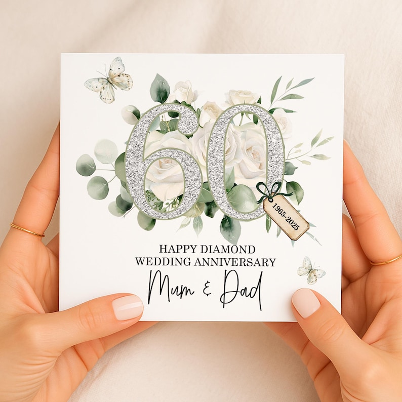 May include: A white square card with a floral design and the number 60 in silver glitter. The card reads "Happy Diamond Wedding Anniversary Mum & Dad" with butterflies and a tag that says "1965-2025".