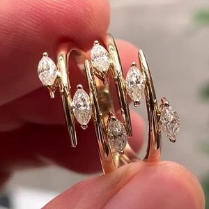 May include: A gold ring with a unique design featuring multiple marquise-shaped diamonds set in a wavy pattern.