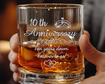 May include: A clear glass tumbler filled with amber liquid and ice, featuring white etched text that reads 10th Anniversary, Ten years down, Forever to go, along with graphic illustrations of two interlocking rings and two small hearts.