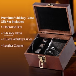 May include: A wooden gift box set with a whiskey glass, steel whiskey cubes, and a leather coaster. The box is open, revealing the contents. The text on the image reads "Premium Whiskey Glass Gift Set Includes: Pinewood Box, Whiskey Glass, 3 Steel Whiskey Cubes, Leather Coaster."