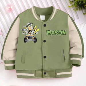 May include: Green and beige baseball jacket with a cartoon image of Goofy and Pluto in a jeep. The jacket has a white stripe on the collar and cuffs and the name "MASON" is printed on the front.