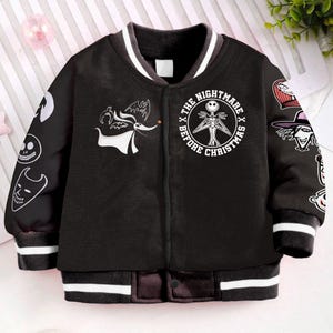 May include: Black bomber jacket with white stripes on the sleeves and collar. The jacket features a large white graphic of Jack Skellington from the movie "The Nightmare Before Christmas" on the front. The back of the jacket has a variety of characters from the movie.