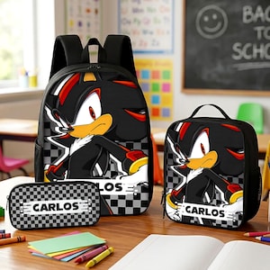 May include: A black backpack, lunch bag, and pencil case set featuring a graphic of the character Shadow the Hedgehog. Each item displays a black and white checkered pattern and a white rectangular label with the name CARLOS printed in black.