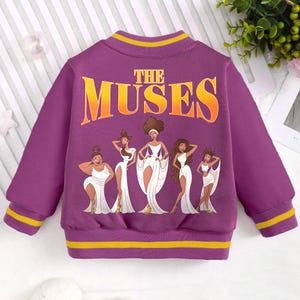 May include: Purple sweatshirt with a yellow stripe around the collar and cuffs. The sweatshirt features a graphic of five women in white dresses with the text "The Muses" above them.