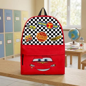 May include: Red backpack with Lightning McQueen's face on the front. The top section has a black and white chequered pattern with racing logos. It has a black handle and a front pocket.