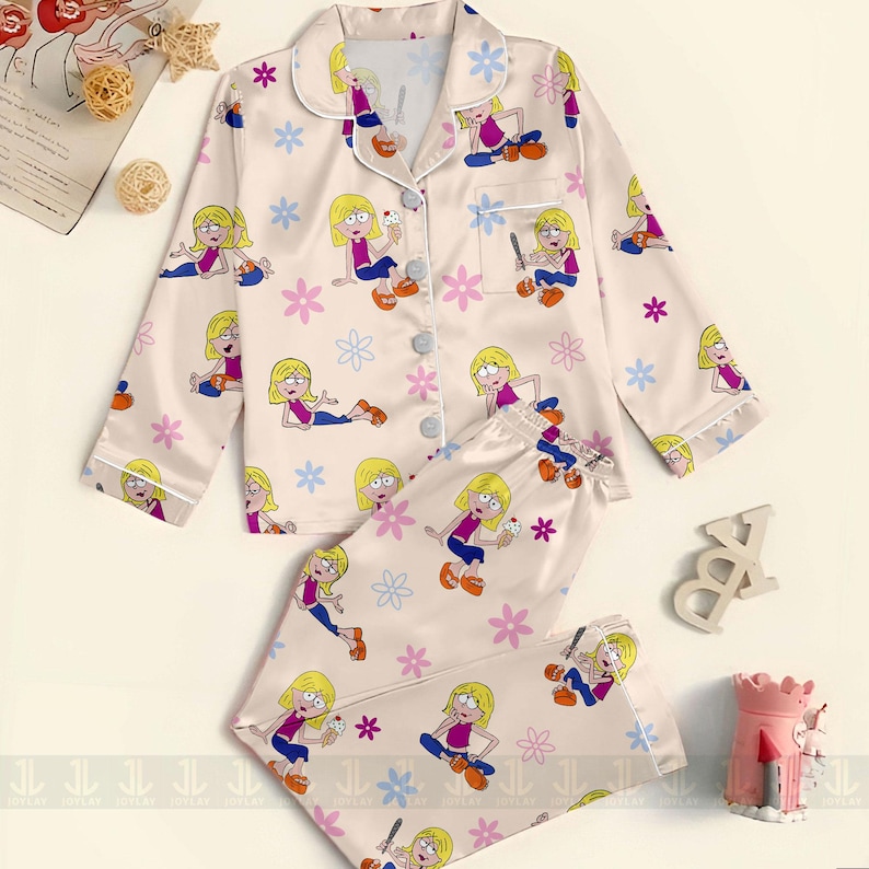 Pu&ograve; includere: Un completo pigiama a due pezzi color crema, con stampa di personaggi dei cartoni animati e dettagli floreali. La parte superiore a maniche lunghe ha una chiusura con bottoni e finiture bianche. I pantaloni coordinati completano il set.