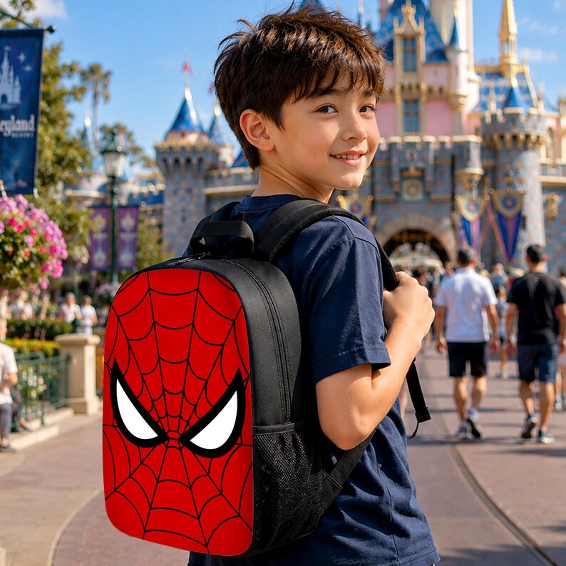 May include: A black backpack featuring a red front panel with a black spiderweb pattern and two large white eye shapes. The backpack has black shoulder straps and side mesh pockets, designed for carrying personal items in a functional manner.