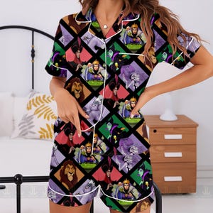 May include: Short-sleeved pajama set featuring a colorful pattern of Disney villains. The set includes a button-down shirt with white trim and matching shorts. The design incorporates various characters in a diamond grid.
