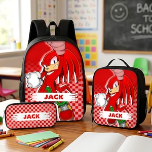 May include: A black backpack, lunch bag, and pencil case set featuring a red and white checkered pattern and a graphic of the character Knuckles. Each item displays the name JACK in bold red letters on a white rectangular background.