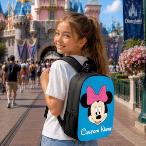 Peut inclure: Un sac &agrave; dos noir avec un panneau bleu vif orn&eacute; d'un motif de Minnie Mouse portant un n&oelig;ud rose. Le texte Custom Name est imprim&eacute; en &eacute;criture blanche sous le personnage. Le sac poss&egrave;de des bretelles noires et des poches lat&eacute;rales en filet.