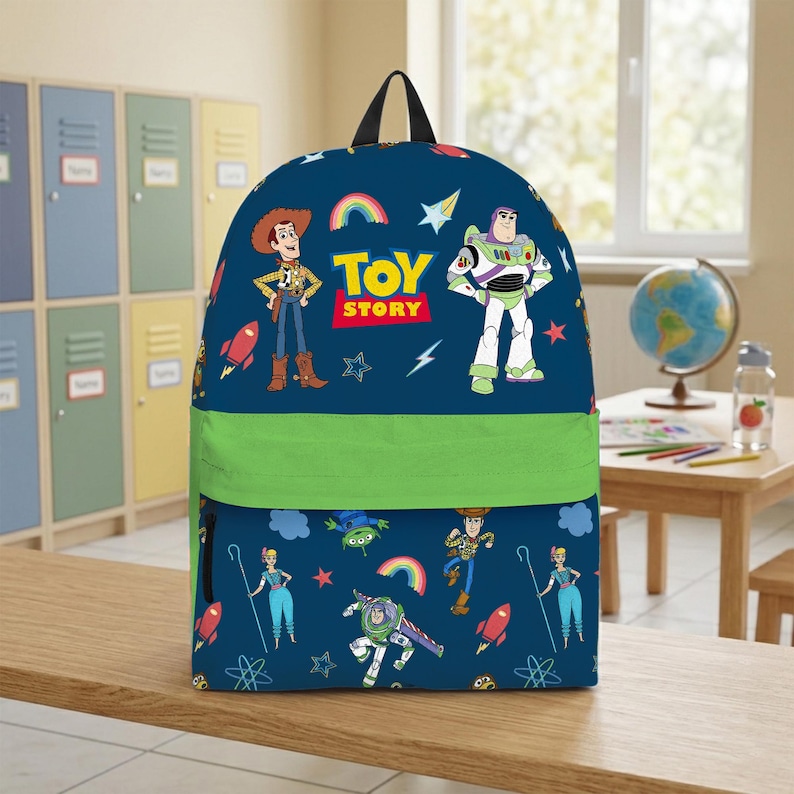 May include: A navy blue backpack featuring characters from the animated film "Toy Story." The backpack has a green band across the middle and a black handle. The design includes Woody, Buzz Lightyear, and the words "Toy Story."