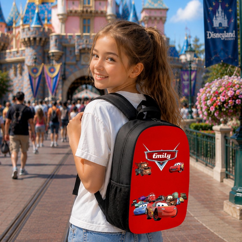 May include: A black backpack with a red front panel featuring the Disney Pixar Cars logo, the name Emily, and various character illustrations from the movie. The backpack has black shoulder straps and side mesh pockets for storage.
